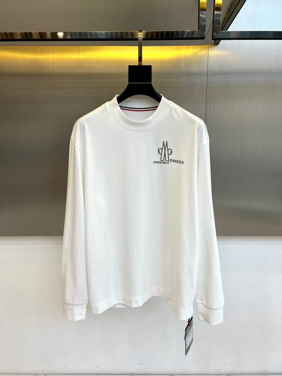 Mon蒙口、2026春夏新品长袖T恤，以经典圆领与利落长袖剪裁，诠释都市休闲风尚。其设计亮点在于领口处精