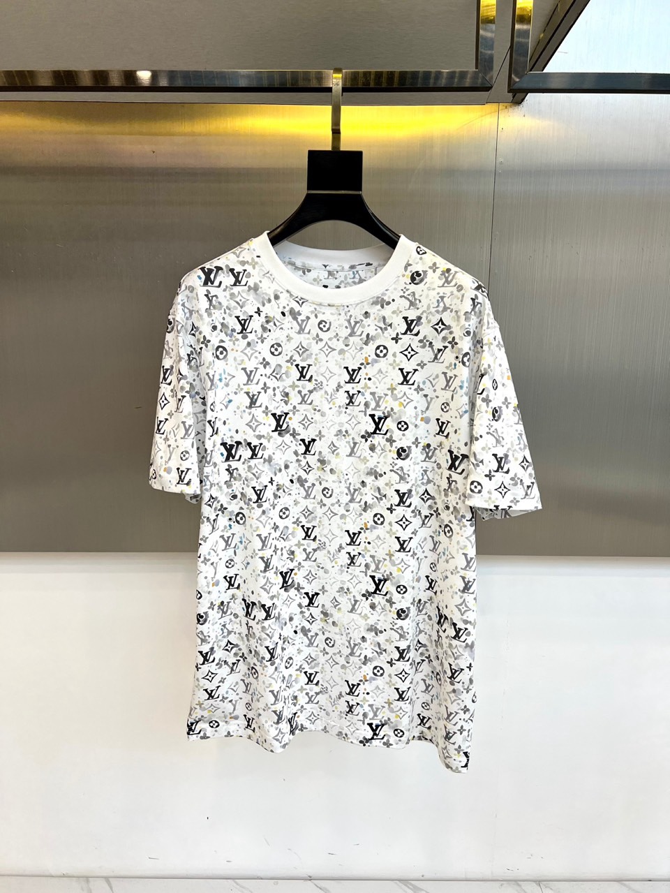 1v威登、2026春夏系列男士T恤，以宽松圆领廓形焕新经典。衣身满印品牌标志性字母组合图案，通过规律且密