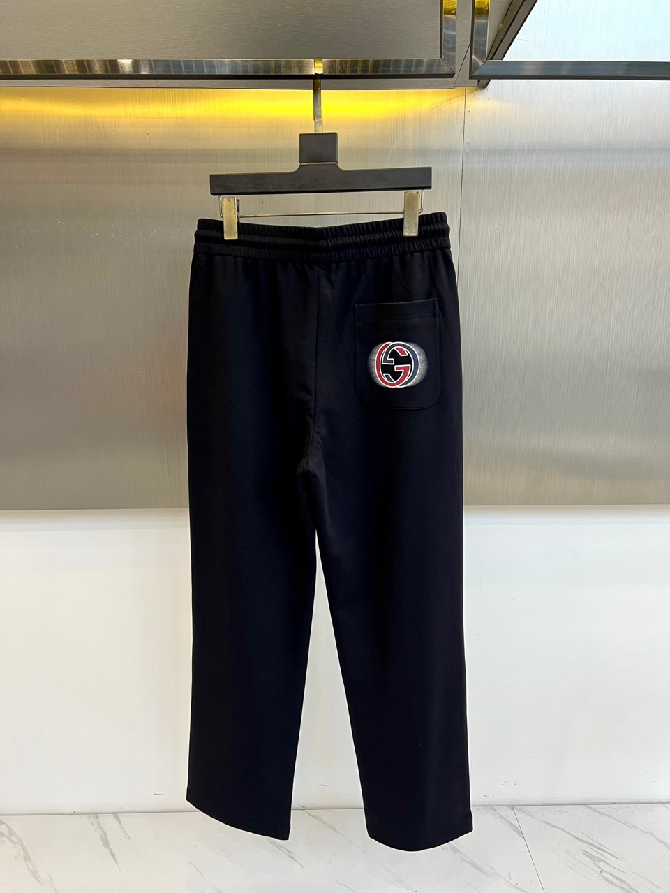 Gucc古驰、2026春夏男士休闲裤，以宽松剪裁重塑当代休闲美学。标志性设计在于裤身正面醒目的品牌刺绣标