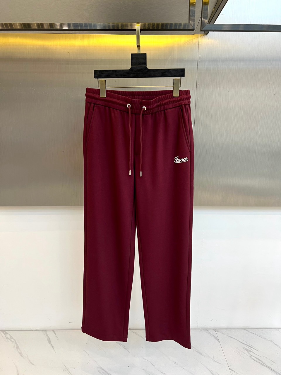 Gucc古驰、2026春夏男士休闲裤，以宽松剪裁重塑当代休闲美学。标志性设计在于裤身正面醒目的品牌刺绣标