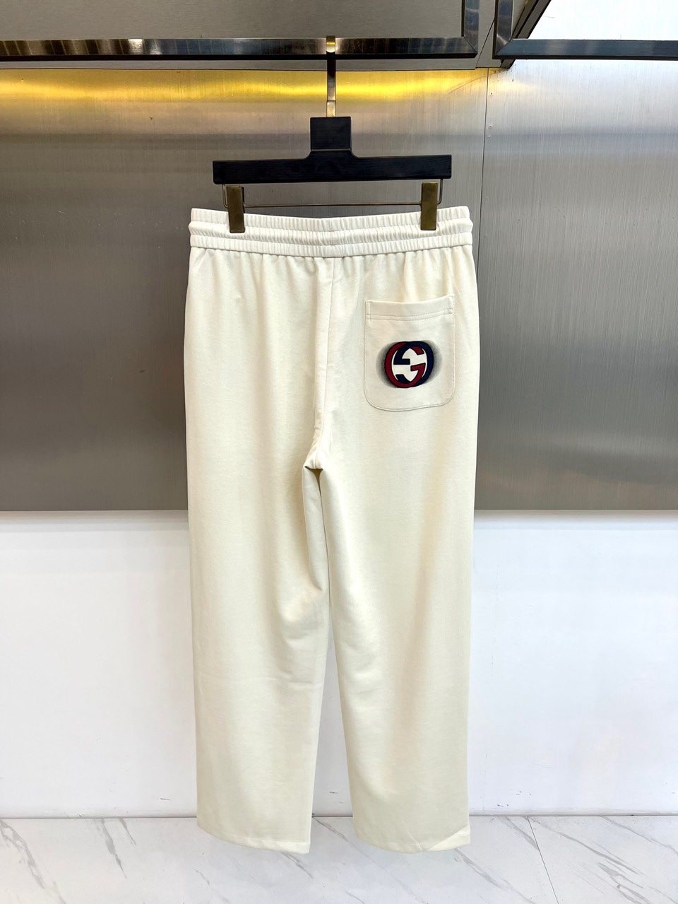 Gucc古驰、2026春夏男士休闲裤，以宽松剪裁重塑当代休闲美学。标志性设计在于裤身正面醒目的品牌刺绣标