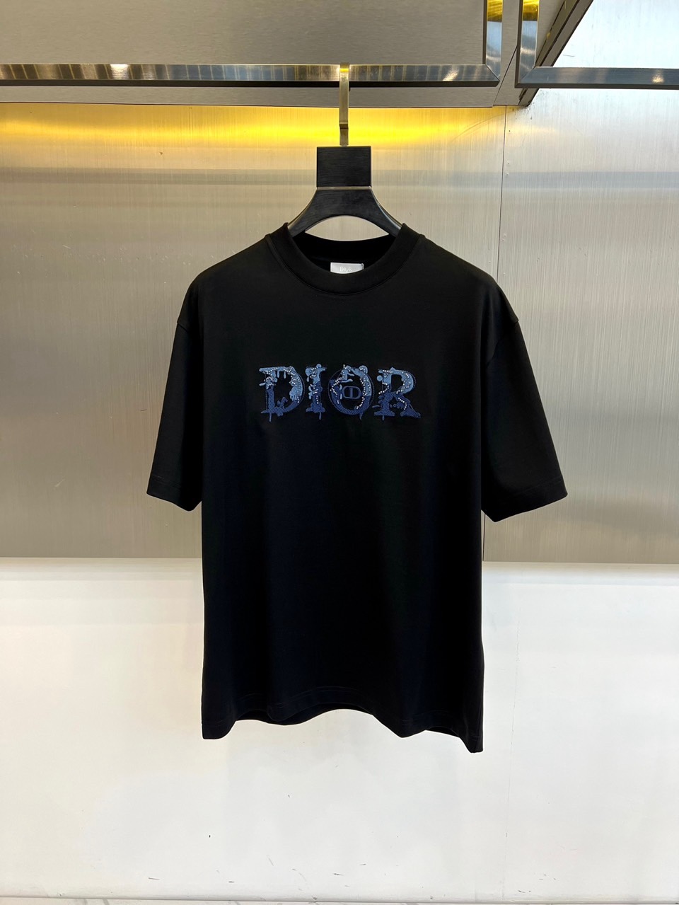 Dio迪奥、2026春夏男士T恤，以摩登手法演绎品牌基因。款式采用宽松圆领剪裁，落肩设计赋予肩线自然弧度