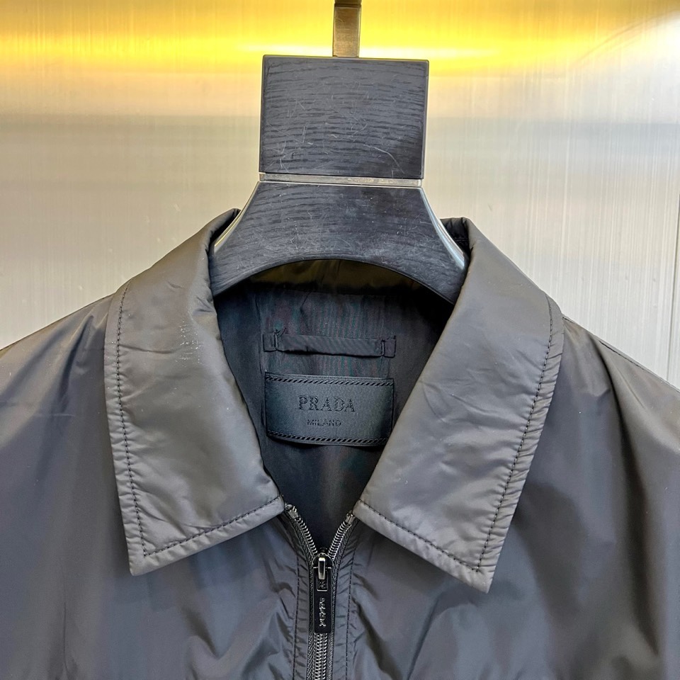 Prad普拉达、2026春夏男士夹克，以简约线条重塑都市机能美学。款式采用经典翻领与顺滑拉链开合，线条利