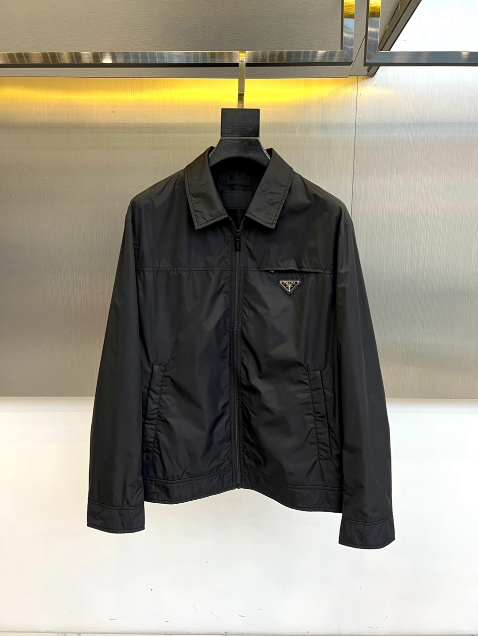 Prad普拉达、2026春夏男士夹克，以简约线条重塑都市机能美学。款式采用经典翻领与顺滑拉链开合，线条利
