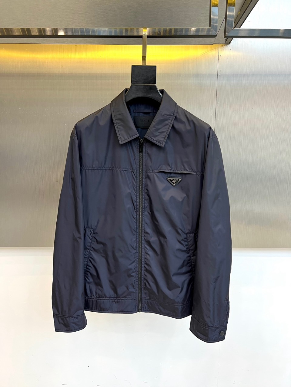 Prad普拉达、2026春夏男士夹克，以简约线条重塑都市机能美学。款式采用经典翻领与顺滑拉链开合，线条利