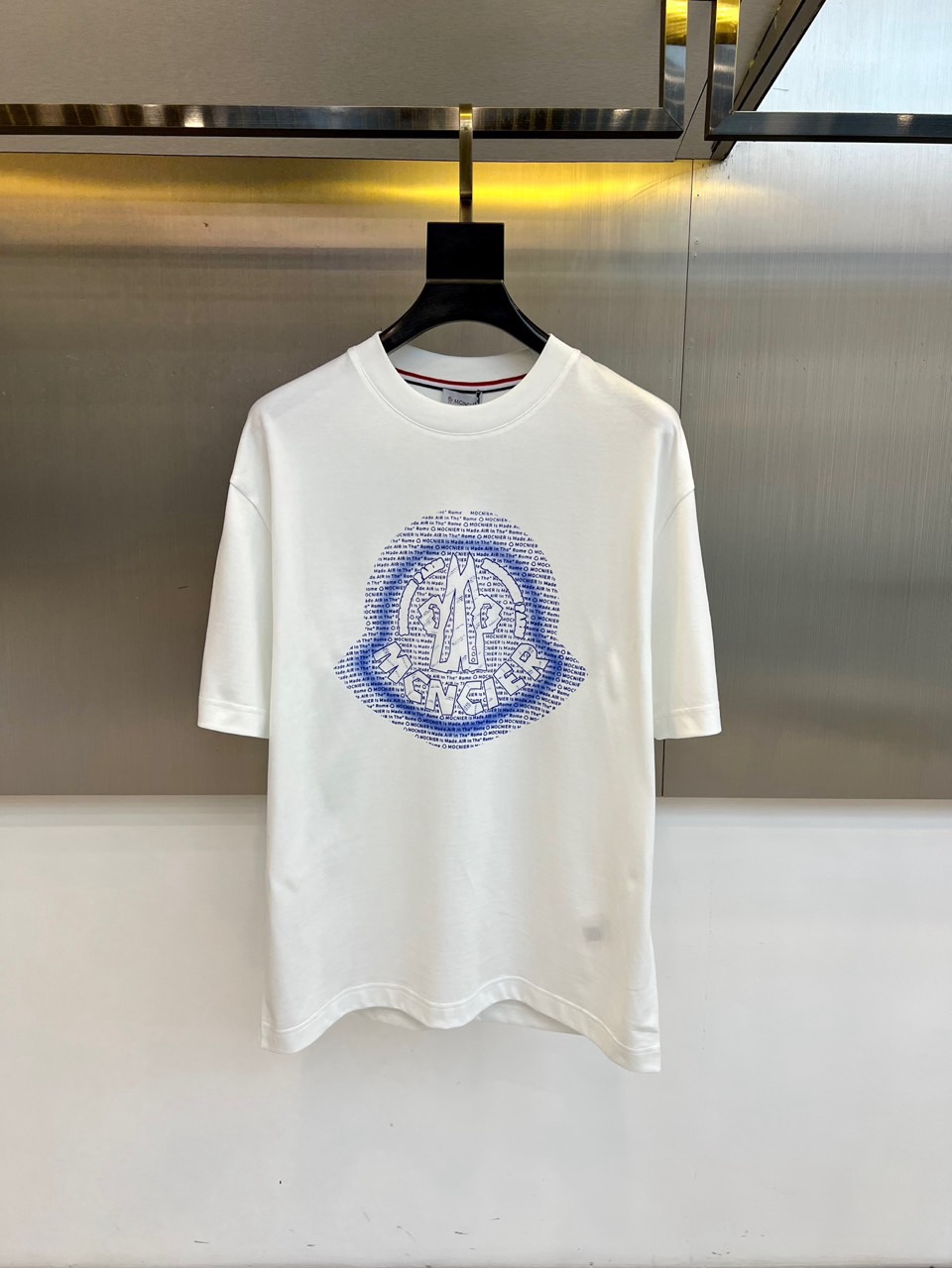 Mon蒙口、2026春夏T恤，以经典圆领短袖廓形展现纯粹休闲感。设计焦点在于衣身正面的品牌标志性图案，由