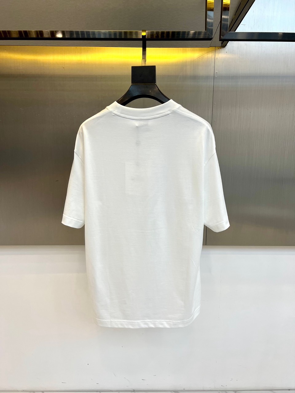 Mon蒙口、2026春夏T恤，以经典圆领短袖廓形展现纯粹休闲感。设计焦点在于衣身正面的品牌标志性图案，由