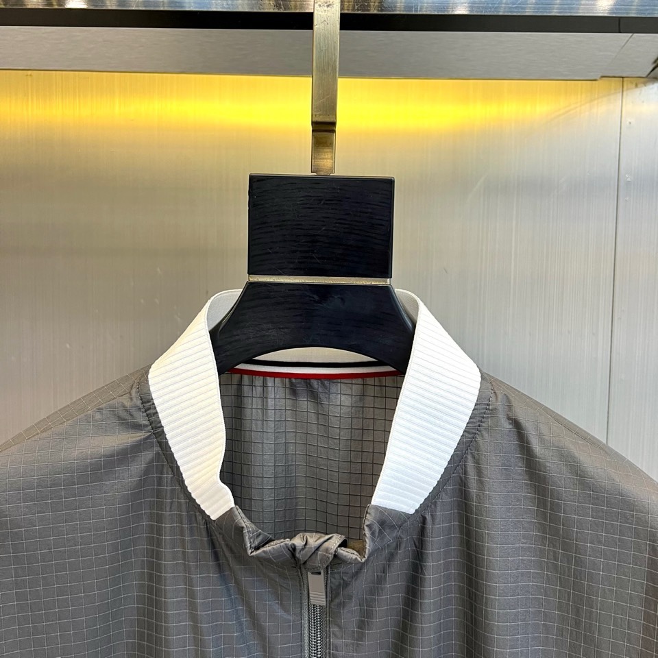 TB汤姆布朗、2026春夏新品夹克，以利落棒球领设计开篇，罗纹领口、下摆与袖口形成经典撞色，袖身四条条纹