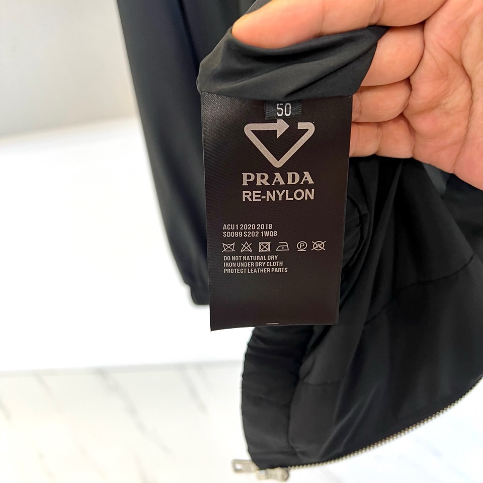 Prad普拉、2026春夏新品男士夹克，以简约立领设计勾勒利落廓形。胸前点缀标志性的金属三角徽标，于极简