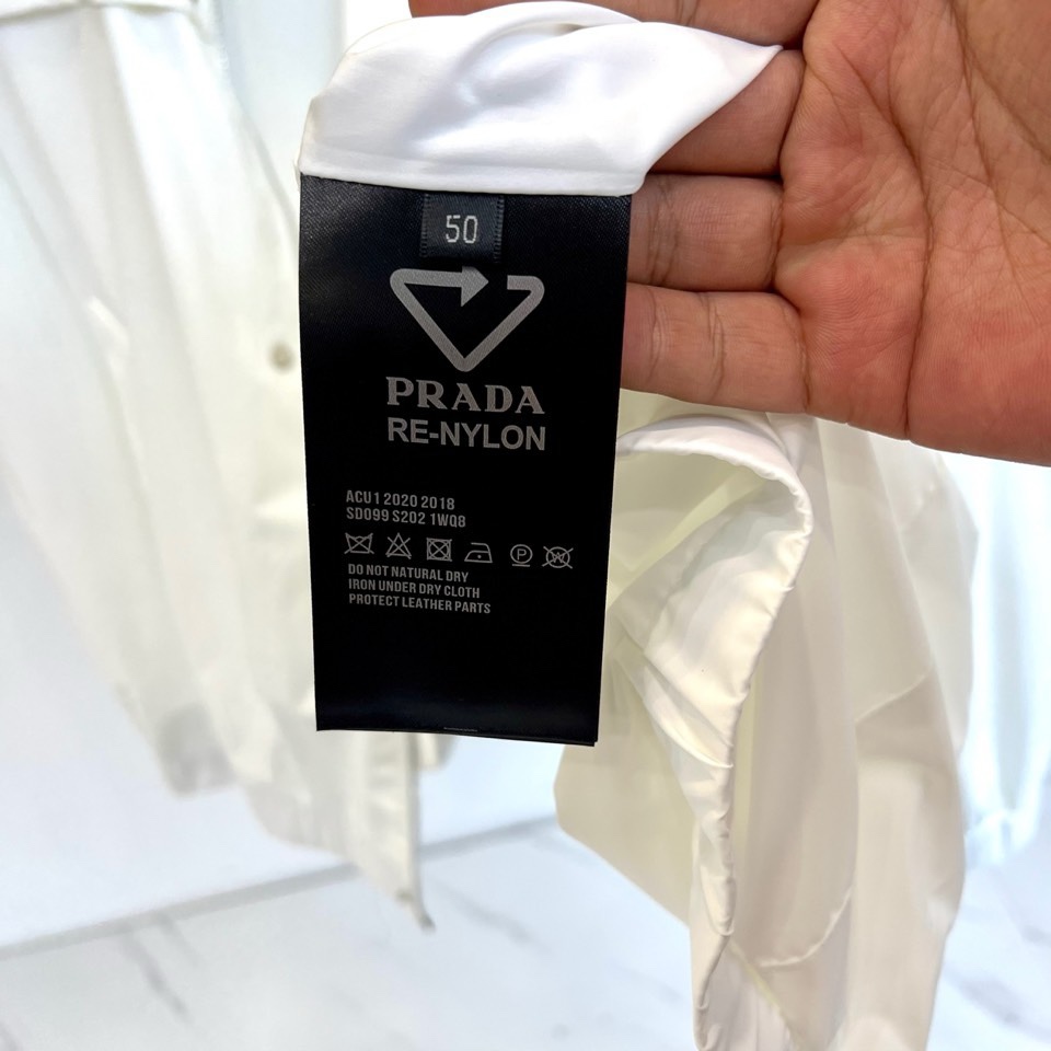 Prad普拉、2026春夏新品男士夹克，以简约立领设计勾勒利落廓形。胸前点缀标志性的金属三角徽标，于极简