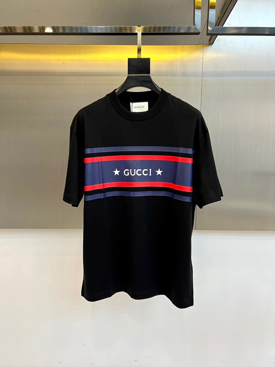 Gucc古驰、2026春夏新品短袖T恤，以经典纯色为底色，胸前横贯撞色条纹，中央“GUCCI”字样搭配两