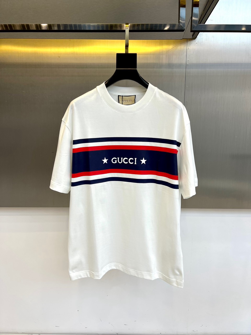 Gucc古驰、2026春夏新品短袖T恤，以经典纯色为底色，胸前横贯撞色条纹，中央“GUCCI”字样搭配两