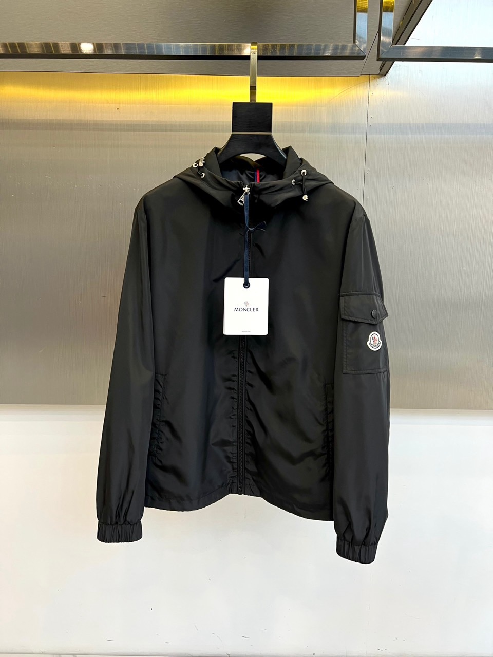 NO:760779,Mon, a new jacket for spring and summer 2026, has a hooded design with drawstring adjustment, which is both functional and stylish. The front zipper closure, and the diagonal pockets on both sides are equipped with metal zippers, which are practical and enhance the level. The brand badge on the left arm is a low-key accent and continues the classic recognition. The fabric is light and crisp, with windproof and breathable properties, suitable for various scenes in spring and summer. The cuffs and hem are elasticated to modify the body shape and enhance practicality.  Sexy. The overall style combines urban leisure and outdoor functions. It can be paired with T-shirts, shirts or sweaters to easily manage commuting, traveling or light business occasions. The minimalist silhouette interprets high-end texture and shows a low-key luxury fashion attitude. It is an ideal choice for both practical wear and style in the spring and summer wardrobe. 48-56 (model 173, 143 pounds, upper body size 50), Moncler, jackets  & coats,shirts,tees,t-shirt,hats,19860909Mon蒙口、2026春夏新品夹克,连帽设计搭配抽绳调节,兼具功能性与造型感.正面拉链开合,两侧斜插口袋配金属拉链,实用且提升层次.左臂品牌徽章低调点睛,延续经典辨识度.面料轻盈挺括,具备防风透气特性,适配春夏多场景穿搭.袖口与下摆松紧收口,修饰身形且增强实用性.整体风格融合都市休闲与户外机能,可搭配T恤、衬衫或针织衫,轻松驾驭通勤、出游或轻商务场合.以极简廓形诠释高级质感,展现低调奢华的时尚态度,是春夏衣橱中兼具实穿与格调的理想之选.48-56（模特173,143斤上身50码）,,Moncler,jackets & coats,shirts,tees，t-shirt,hats,,Men's clothing