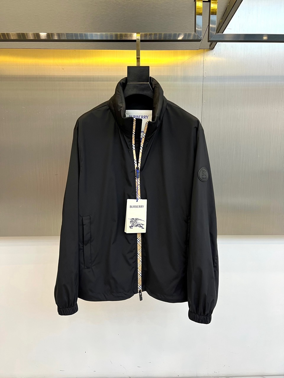 NO:760807,Burberry's 2026 spring and summer new stand-up collar jacket outlines the silhouette of an urban man with neat tailoring. The classic stand-up collar design has both windproof function and fashionable aura, and is easily suitable for commuting and leisure scenes. The jacket is made of light and crisp high-density fabric, which is smooth to the touch, anti-wrinkle and durable. The main tone is calm and versatile, low-key and mid-key  It reveals a high-end texture. The diagonal pockets on both sides of the body are practical without damaging the overall line. The cuffs and hem are elastically tied to improve wearing comfort and windproof performance. The lining is decorated with the brand's signature plaid pattern, and the zipper opening is decorated with the same plaid trim. The details highlight British ingenuity. The round badge on the left arm is low-key embellishment, which matches the chest  The hanging war horse tag echoes and strengthens brand recognition. The overall style combines modern sports style with classic British elegance. It is suitable for pairing with jeans to create a casual street style, or with trousers for a sophisticated business casual style. The 2026 spring and summer series continues the brand's dedication to quality and details, combining pragmatism with the times.  The perfect balance of fashion and aesthetics, it is an indispensable and versatile item in the wardrobe, helping you to stand out calmly on the streets in spring, showing confidence in every step. 48-56 (model weighs 173,143 pounds, upper body size 50),, burberry, burberry, jeans, jackets  & coats,jackets & coats,19860909Bur巴宝莉、2026春夏新品立领夹克,以利落剪裁勾勒都市型男轮廓,经典立领设计兼具防风功能与时尚气场,轻松适配通勤与休闲场景.外套采用轻盈挺括的高密度面料,触感顺滑且抗皱耐穿,主调沉稳百搭,低调中透出高级质感.衣身两侧斜插口袋实用且不破坏整体线条,袖口与下摆弹性收束,提升穿着舒适度与防风性能.内衬饰以品牌标志性格纹,拉链开合处点缀同款格纹饰边,细节处彰显英伦匠心.左臂圆形徽章低调点缀,与胸前悬挂的战马吊牌相呼应,强化品牌辨识度.整体风格融合现代运动风与经典英伦优雅,既适合搭配牛仔裤打造随性街头造型,也可配西裤演绎精致商务休闲风.2026春夏系列延续品牌对品质与细节的执着,将实用主义与时尚美学完美平衡,是衣橱中不可或缺的百搭单品,助你在春日街头从容出众,步履间尽显自信风范.48-56（模特173,143斤上身50码）,,burberry,burberry,jeans,jackets & coats,jackets & coats,,Men's clothing