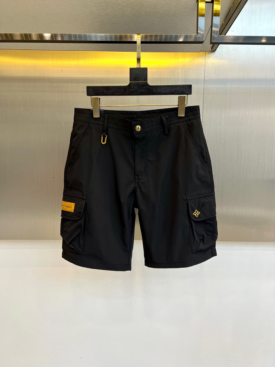 NO:918389,1v Vuitton, 2026 spring and summer new cargo shorts, combine a classic workwear style with a multi-pocket functional design to create a neat and stylish style. Its style perfectly blends urban fashion and outdoor functionality, easily adapting to diverse scenes from daily travel to leisure exploration. Fabric selection  Made of stiff and wear-resistant high-quality materials, it ensures a stylish silhouette and long-lasting practicality when worn. The detailed craftsmanship highlights the luxurious gene. The front is decorated with the brand's iconic exquisite hardware fasteners and embroidery; in particular, the side pockets are decorated with unique metal pendants, with 'XI' engraved on them.  The words 'YI ZHU 1981' give the single product a collection meaning like an artistic signature, injecting delicate craftsmanship into the roughness. 48-56 (please quote waist size when placing an order),, shorts,198609091v威登、2026春夏新品工装短裤,以经典工装版型结合多口袋功能设计,打造利落有型的款式.其风格完美融合都市时尚与户外机能感,轻松适配从日常出行到休闲探索的多元场景.面料选用挺括耐磨的优质材质,确保穿着时的有型轮廓与持久耐用的实用性.细节工艺彰显奢华基因正面饰有品牌标志性的精致五金扣件与刺绣；特别的是,侧面口袋点缀独特金属挂饰,其上镌刻“XI YI ZHU 1981”字样,赋予单品艺术署名般的收藏意义,于粗犷中注入细腻匠心.48-56（下单请报腰围尺寸）,,shorts,,Men's clothing