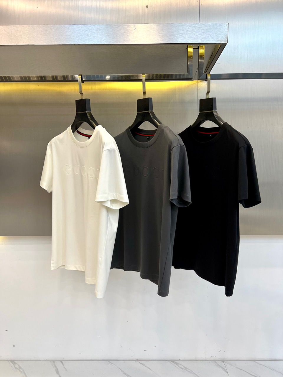 Gucc古驰、2026春夏新品短袖T恤，以纯色为基底，胸前采用立体压花工艺呈现品牌字母标识，简约中暗藏精