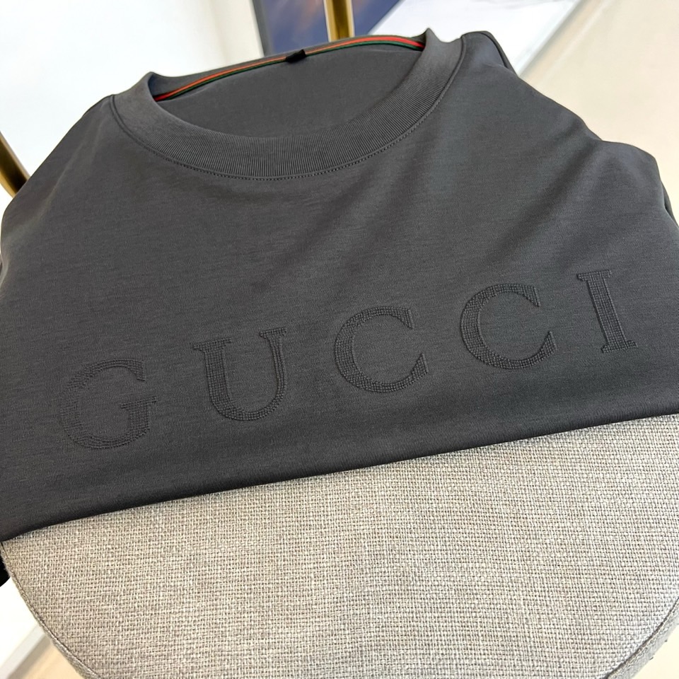 Gucc古驰、2026春夏新品短袖T恤，以纯色为基底，胸前采用立体压花工艺呈现品牌字母标识，简约中暗藏精