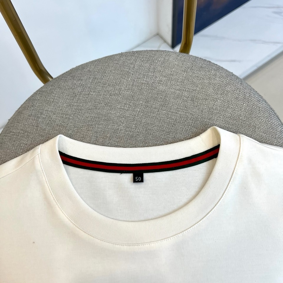 Gucc古驰、2026春夏新品短袖T恤，以纯色为基底，胸前采用立体压花工艺呈现品牌字母标识，简约中暗藏精