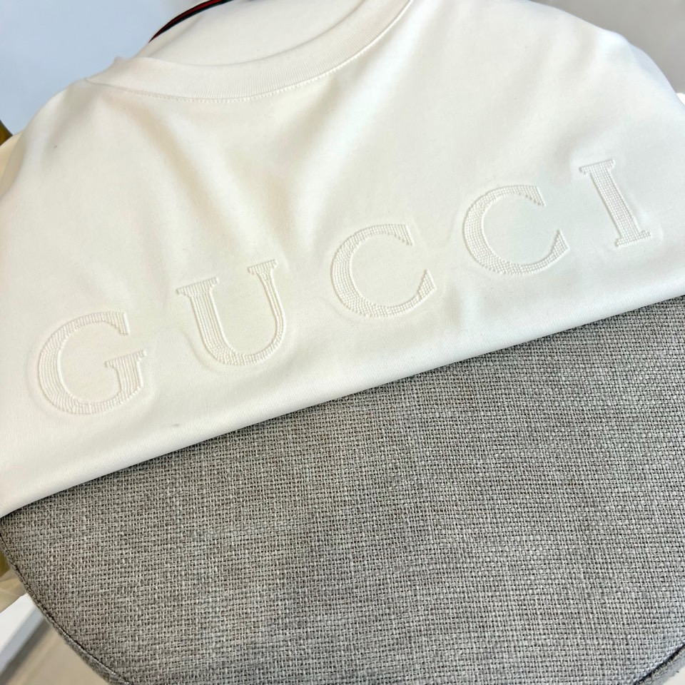 Gucc古驰、2026春夏新品短袖T恤，以纯色为基底，胸前采用立体压花工艺呈现品牌字母标识，简约中暗藏精
