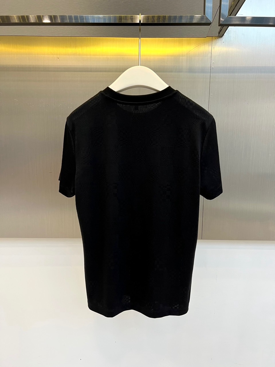 1v威登、2026春夏新品短袖T恤，以纯色为基底，满幅暗纹棋盘格肌理低调奢华，胸前精致字母刺绣点缀，简约