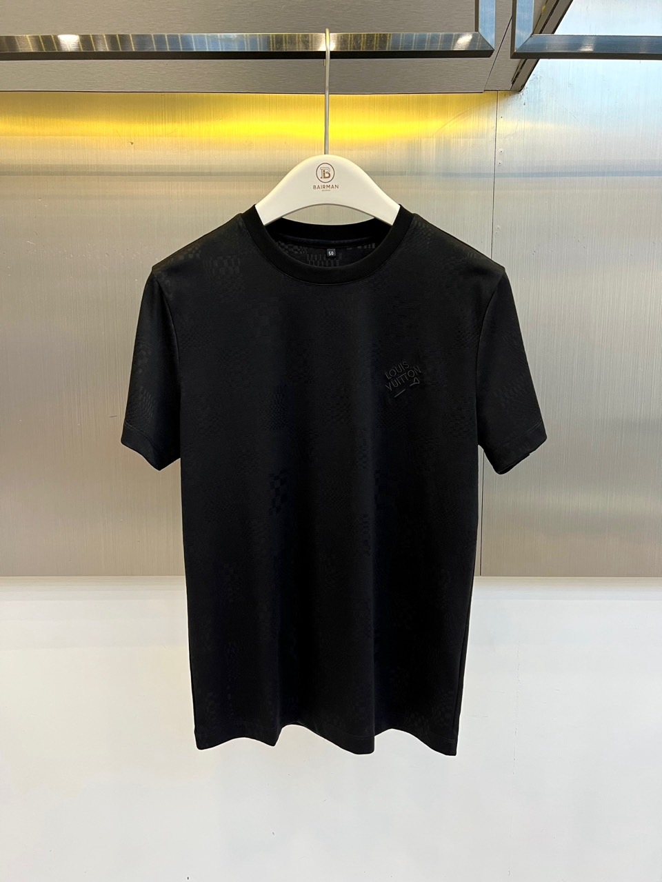 1v威登、2026春夏新品短袖T恤，以纯色为基底，满幅暗纹棋盘格肌理低调奢华，胸前精致字母刺绣点缀，简约