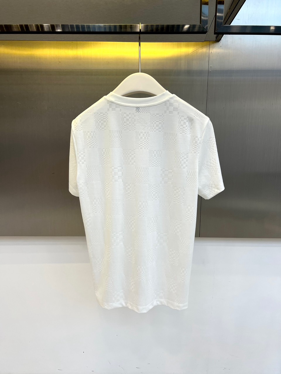 1v威登、2026春夏新品短袖T恤，以纯色为基底，满幅暗纹棋盘格肌理低调奢华，胸前精致字母刺绣点缀，简约
