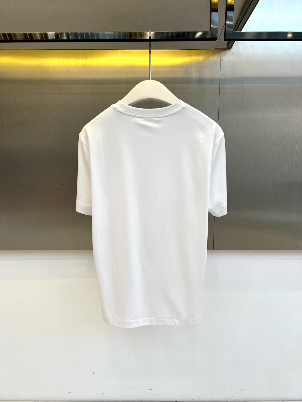 Mon蒙口、2026春夏新品短袖T恤，以纯色为基底，诠释极简主义美学。领子上精致字母标识点缀，低调彰显品