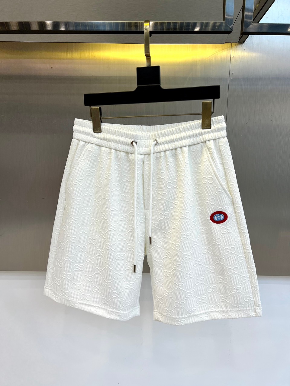 NO:830764,Gucci, 2026 new spring and summer shorts are mainly in solid colors, and the all-over three-dimensional jacquard process presents the classic double G pattern, which highlights the luxurious texture in a low-key manner. It adopts an elastic waistband with a drawstring design, which can be easily adjusted to fit the waist and is comfortable to wear. The fabric is made of breathable mesh texture, which is light and sweat-wicking, perfect for the hot weather in spring and summer. A contrasting round badge is embellished on the left side, which is a simple version.  Add visual focus and brand recognition. The overall style combines street casual and light luxury sports aesthetics. The loose straight cut modifies the leg lines, which is both fashionable and practical. It is an indispensable and versatile item in the spring and summer wardrobe, helping you easily interpret the high-end street style. 48-56 (model is 173, 143 pounds, upper body size 50),, gucci, gucci, shorts,19860909Gucc古驰、2026春夏新品短裤以纯色为主调,满幅立体提花工艺呈现经典双G图案,低调中彰显奢华质感.采用松紧腰头搭配抽绳设计,轻松调节贴合腰身,穿着舒适自在.面料选用透气网眼肌理,轻盈排汗,完美应对春夏季节的炎热天气.左侧点缀撞色圆形徽章,为简约版型增添视觉焦点与品牌辨识度.整体风格融合街头休闲与轻奢运动美学,宽松直筒剪裁修饰腿部线条,兼具时尚感与实穿性,是春夏衣橱中不可或缺的百搭单品,助你轻松演绎高级街头风潮.48-56（模特173,143斤上身50码）,,gucci,gucci,shorts,,Men's clothing