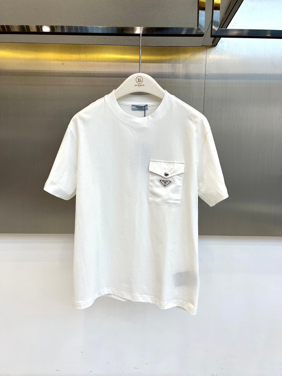 NO:830795,Prad, the new short-sleeved T-shirt for spring and summer 2026, uses solid colors as the main color to interpret the high-end texture of minimalism. The classic round neck design fits the neck line, the short-sleeved cut is neat and stylish, and the loose silhouette is both comfortable and casual, easily suitable for daily commuting or casual outings. Left chest  The iconic triangular logo pockets are embellished everywhere, and the metallic badges form a delicate contrast with the simple bottom, highlighting the brand recognition and design ingenuity in a low-key manner. The fabric is made of high-count combed cotton, which is smooth and breathable, with excellent moisture absorption and perspiration performance, making it refreshing and not stuffy to wear in spring and summer. The hem of the body is naturally draped,  The edges are neatly routed, and the details reflect craftsmanship. The overall style combines modern urban feel with light luxury style. It can be worn as a basic item layered or worn alone to show a clean and neat temperament. The 2026 spring and summer series continues the brand’s pursuit of quality and aesthetics. This short-sleeved shirt is not only a wardrobe must-have  Basic models are prepared, which are fashion statements that highlight taste and attitude, making every time you wear them an expression of confidence. 48-56 (model weighs 173,143 pounds, upper body size 50), prada, prada, T-shirt, tees, t-shirt,19860909Prad普拉达、2026春夏新品短袖T恤,以纯色为主调,诠释极简主义的高级质感.经典圆领设计贴合颈部线条,短袖剪裁利落有型,宽松廓形兼顾舒适与随性,轻松适配日常通勤或休闲出街.左胸处点缀标志性三角徽标口袋,金属质感徽章与简约底形成精致对比,低调中彰显品牌辨识度与设计巧思.面料选用高支精梳棉,触感柔滑透气,吸湿排汗性能优异,春夏穿着清爽不闷热.衣身下摆自然垂坠,边缘走线工整,细节处体现匠心工艺.整体风格融合现代都市感与轻奢格调,既可作为基础单品叠穿,亦可单穿展现干净利落气质.2026春夏系列延续品牌对品质与美学的追求,这款短袖不仅是衣橱必备基础款,更是彰显品味与态度的时尚宣言,让每一次穿着都成为自信表达.48-56（模特173,143斤上身50码）,,prada,prada,T-shirt,tees，t-shirt,,Men's clothing