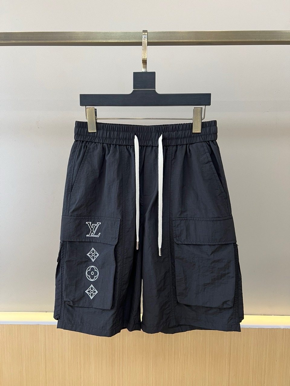 NO:918377,1v Vuitton, the new 2026 spring and summer cargo shorts, interpret the perfect balance between street fashion and pragmatism. The loose silhouette is tailored with an elastic drawstring waist, and the drawstring details add sporty vitality, adapt to various body shapes while bringing a comfortable and comfortable wearing experience. The two-sided three-dimensional large pocket design enhances functional attributes, and the right pocket is cleverly embellished with the brand's classic letter logo and geometric totems, using exquisite lines to outline a low-key sense of luxury.  Shows extraordinary taste. The fabric is made of light and breathable technical materials, with both crisp texture and quick-drying performance, which can perfectly cope with the changeable climate of spring and summer. The overall style combines elements of high street workwear and casual sports, which can be easily controlled whether it is urban commuting or outdoor exploration, instantly improving the layering of the style and creating a trendy attitude of this season. M-4XL (model is 173, 143 pounds, upper body size L),, shorts,198609091v威登、2026春夏新品工装短裤,诠释街头潮流与实用主义的完美平衡.宽松廓形剪裁配合松紧抽绳腰头,抽绳细节增添运动活力,适配多元身形同时带来舒适自在的穿着体验.双侧立体大口袋设计强化机能属性,右侧口袋巧妙点缀品牌经典字母标识与几何图腾,以精致线条勾勒出低调奢华感,彰显不凡品味.面料选用轻盈透气的科技材质,兼具挺括质感与速干性能,完美应对春夏多变气候.整体风格融合高街工装与休闲运动元素,无论是都市通勤还是户外探索都能轻松驾驭,瞬间提升造型层次感,打造属于本季的潮流态度.M-4XL（模特173,143斤上身L码）,,shorts,,Men's clothing