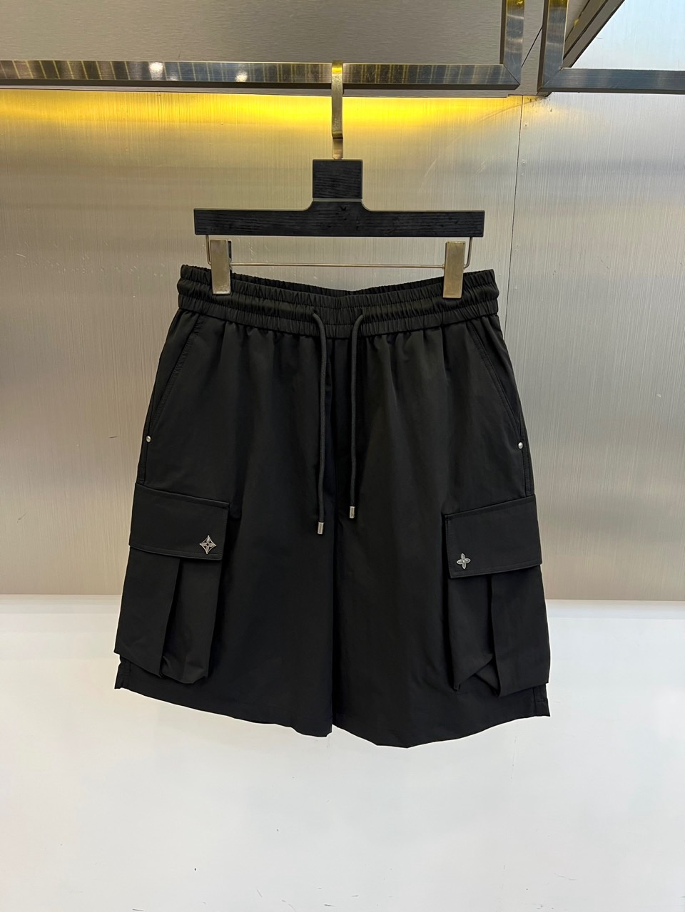 NO:918371,1v Vuitton, 2026 spring and summer new cargo shorts, continue the classic Cargo  Pocket design, two-dimensional three-dimensional large pockets on both sides combine practicality and style. The drawstring elastic waistband adapts to various body shapes and easily creates a casual street posture. The fabric is made of light and breathable cotton blend material, which is soft and skin-friendly, making it comfortable to wear in spring and summer.  It's refreshing but not stuffy, and the drapey fabric naturally modifies the shape of your legs, giving you a lazy atmosphere when walking around. The details are embellished with metal buttons and exquisite brand logos, highlighting quality in a low-key manner. The overall style combines the tough lines of Japanese workwear with the looseness of American leisure.  It has a neat silhouette with outdoor functions without losing the trendy attitude of urban streets. Whether it is daily commuting, weekend outings or sports and fitness, it can be easily controlled and shows an effortless sense of fashion. In the spring and summer of 2026, these cargo shorts will become  A versatile tool for your wardrobe, it uses simple colors and practical designs to interpret the new generation of street aesthetics, and can easily wear the perfect balance of high-end and comfort. M-4XL (model weighs 173,143 pounds, upper body size L),,shorts,198609091v威登、2026春夏新品工装短裤,延续经典Cargo Pocket设计,双侧立体大口袋兼具实用性与造型感,抽绳松紧腰头适配各种身形,轻松打造随性街头姿态.面料选用轻薄透气的棉质混纺材质,触感柔软亲肤,春夏穿着清爽不闷热,垂坠感十足的面料自然修饰腿型,走动间自带慵懒氛围.细节处点缀金属纽扣与精致品牌标识,低调中彰显品质.整体风格融合日系工装的硬朗线条与美式休闲的松弛感,既有户外机能的利落轮廓,又不失都市街头的潮流态度.无论是日常通勤、周末出游还是运动健身,都能轻松驾驭,展现不费力的时髦感.2026春夏,让这条工装短裤成为你衣橱里的百搭利器,用简约色彩与实用设计诠释新一代街头美学,轻松穿出高级感与舒适度的完美平衡.M-4XL（模特173,143斤上身L码）,,shorts,,Men's clothing