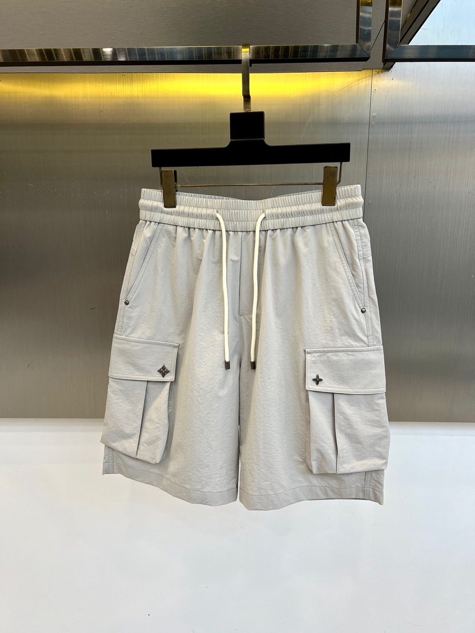 NO:918365,1v Vuitton, 2026 spring and summer new cargo shorts, continue the classic Cargo  Pocket design, two-dimensional three-dimensional large pockets on both sides combine practicality and style. The drawstring elastic waistband adapts to various body shapes and easily creates a casual street posture. The fabric is made of light and breathable cotton blend material, which is soft and skin-friendly, making it comfortable to wear in spring and summer.  It's refreshing but not stuffy, and the drapey fabric naturally modifies the shape of your legs, giving you a lazy atmosphere when walking around. The details are embellished with metal buttons and exquisite brand logos, highlighting quality in a low-key manner. The overall style combines the tough lines of Japanese workwear with the looseness of American leisure.  It has a neat silhouette with outdoor functions without losing the trendy attitude of urban streets. Whether it is daily commuting, weekend outings or sports and fitness, it can be easily controlled and shows an effortless sense of fashion. In the spring and summer of 2026, these cargo shorts will become  A versatile tool for your wardrobe, it uses simple colors and practical designs to interpret the new generation of street aesthetics, and can easily wear the perfect balance of high-end and comfort. M-4XL (model weighs 173,143 pounds, upper body size L),,shorts,198609091v威登、2026春夏新品工装短裤,延续经典Cargo Pocket设计,双侧立体大口袋兼具实用性与造型感,抽绳松紧腰头适配各种身形,轻松打造随性街头姿态.面料选用轻薄透气的棉质混纺材质,触感柔软亲肤,春夏穿着清爽不闷热,垂坠感十足的面料自然修饰腿型,走动间自带慵懒氛围.细节处点缀金属纽扣与精致品牌标识,低调中彰显品质.整体风格融合日系工装的硬朗线条与美式休闲的松弛感,既有户外机能的利落轮廓,又不失都市街头的潮流态度.无论是日常通勤、周末出游还是运动健身,都能轻松驾驭,展现不费力的时髦感.2026春夏,让这条工装短裤成为你衣橱里的百搭利器,用简约色彩与实用设计诠释新一代街头美学,轻松穿出高级感与舒适度的完美平衡.M-4XL（模特173,143斤上身L码）,,shorts,,Men's clothing