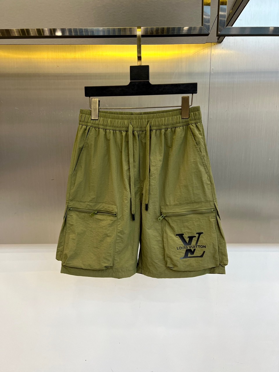 NO:918391,1v Vuitton, the new 2026 spring and summer cargo shorts, set the tone for summer vitality with eye-catching colors. The lightweight technical fabric creates a breathable and crisp texture, taking into account practical wear and comfort. The loose straight cut and elastic waist drawstring design accommodate all body shapes while providing a free and unrestricted wearing experience. The two-sided three-dimensional workwear large pockets are closed with exquisite zippers, which not only enhances functional aesthetics but also has practical storage functions, and shows ingenuity in every detail. The iconic L on the left leg  The V letter is low-key and luxurious, perfectly integrating brand recognition with street trends, presenting a cross-border style between high-end fashion and urban leisure. Based on workwear elements, these shorts are infused with luxury fashion genes, redefining the essential items in men's wardrobe in spring and summer, allowing comfort and style to naturally appear while roaming in the city, showing an avant-garde and uninhibited fashion attitude and exquisite lifestyle. M-4XL (model 173, 143 pounds, upper body size L),, louis  vuitton,shorts,198609091v威登、2026春夏新品工装短裤,以醒目色调定格夏日活力,轻盈科技面料打造透气挺括质感,兼顾实穿性与舒适度.宽松直筒剪裁配合弹力腰头抽绳设计,包容各种身形同时提供自由无束的穿着体验.双侧立体工装大口袋搭配精致拉链闭合,既强化机能美学又兼具实用收纳功能,细节处彰显匠心.左腿处标志性LV字母低调奢华,将品牌辨识度与街头潮流完美融合,呈现高级时装与都市休闲的跨界风格.这款短裤以工装元素为基调,注入奢华时尚基因,重新定义春夏男士衣橱必备单品,让舒适与型格在都市漫游中自然流露,展现前卫不羁的时尚态度与精致生活品味.M-4XL（模特173,143斤上身L码）,,louis vuitton,shorts,,Men's clothing
