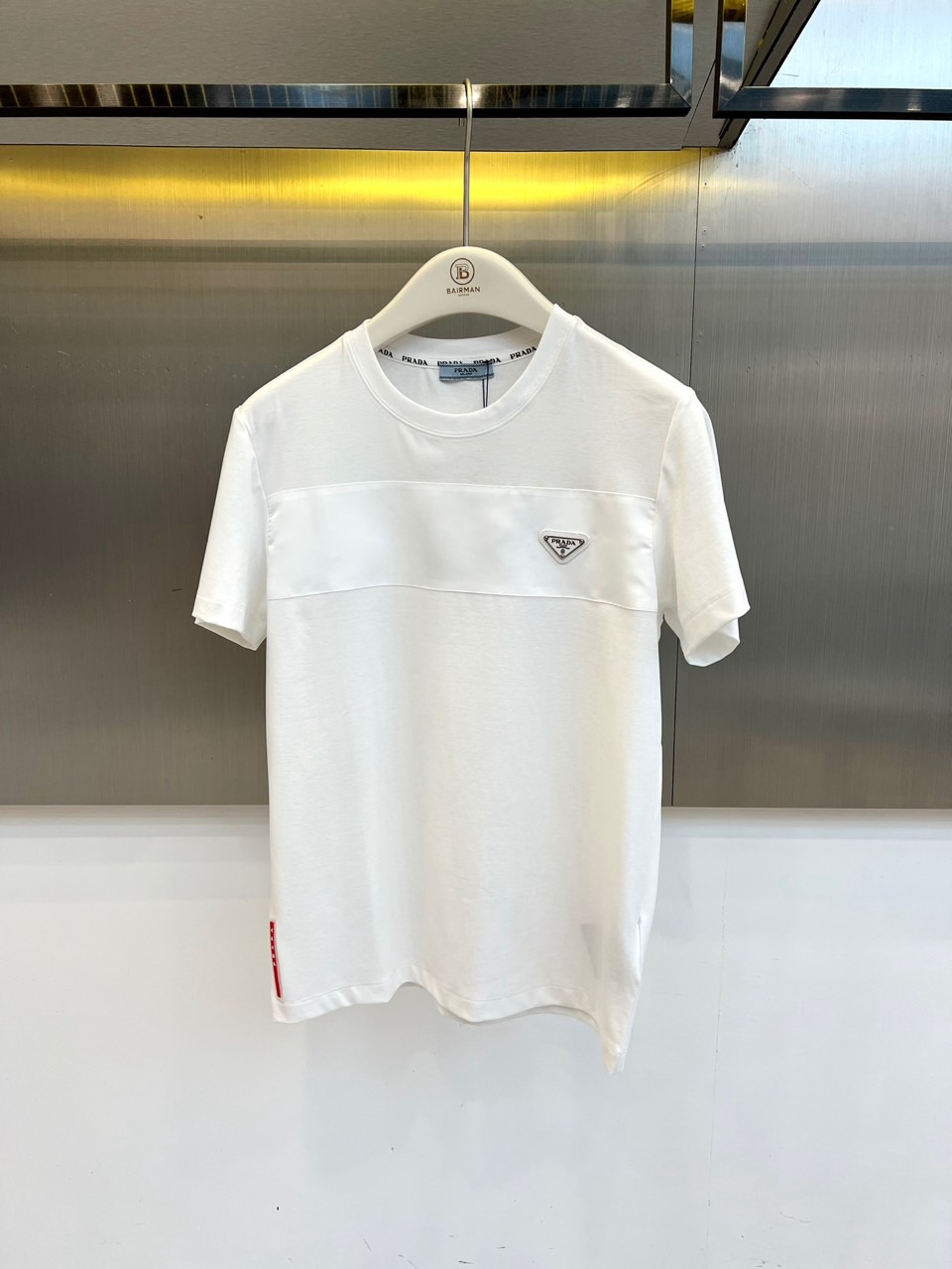 NO:902998,Prad, the new 2026 spring and summer men's round neck short-sleeved T-shirt, presents modern urban aesthetics with a neat and simple silhouette. The solid color tone is clean and pure, and the exquisite triangle logo embellishment on the chest adds brand recognition. The classic elements and contemporary design are perfectly integrated, highlighting  Low-key luxury taste style. Horizontal stitching breaks the monotony of the plane, enriches the visual hierarchy and optimizes body proportions, allowing simple items to shine with unique details. Selected high-count cotton fabrics are soft to the touch and skin-friendly, and have excellent breathability and moisture absorption properties, whether under the scorching sun.  Whether you are commuting in the city or traveling on weekends, you can stay fresh and comfortable all day long. The reinforced rib technology on the neckline ensures long-lasting stiffness and is not easily deformed, and the micro-arc tailoring of the hem makes it more casual. The minimalist style with neat lines makes it easy to control business casual and daily wear, making it a perfect spring and summer garment.  A classic and versatile item that is indispensable for your wardrobe, helping you welcome every highlight moment with a calm attitude. 48-56 (model weighs 173,143 pounds, upper body size 50),, prada, prada, T-shirt, tees, t-shirt,19860909Prad普拉达、2026春夏新品男士圆领短袖T恤,以利落简约的廓形呈现现代都市美学.纯色基调干净纯粹,胸前精致的三角徽标点缀增添品牌辨识度,经典元素与当代设计完美融合,彰显低调奢华的品味格调.横向拼接缝线打破平面单调,丰富视觉层次的同时优化身形比例,让简约单品也能焕发别致细节感.甄选高支棉质面料,触感柔软亲肤,透气吸湿性能出色,无论是烈日下的都市通勤还是周末休闲出行,都能保持全天候清爽舒适.领口加固罗纹工艺确保持久挺括不易变形,下摆微弧剪裁更显随性自在.极简主义风格搭配利落线条,轻松驾驭商务休闲与日常穿搭,是春夏衣橱不可或缺的经典百搭单品,助你以从容姿态迎接每一个高光时刻.48-56（模特173,143斤上身50码）,,prada,prada,T-shirt,tees，t-shirt,,Men's clothing