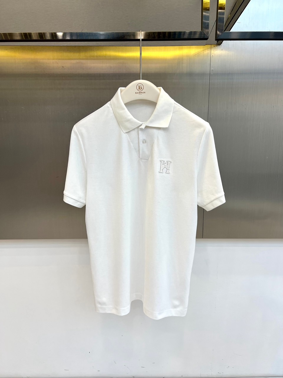 NO:903018,H Hermès, 2026 spring and summer new short-sleeved Polo shirt, interprets modern urban light luxury style with neat tailoring. The classic lapel is matched with two exquisite buttons, which is simple yet elegant. The short-sleeved design fits the arm lines, taking into account the refreshing breathability and  Clean silhouette. The body is made of fine pique cotton fabric, which is smooth to the touch, crisp and stylish, making it light and not stuffy to wear in spring and summer. The left chest is decorated with three-dimensional embroidered logo letters, which low-key highlights the brand recognition and injects exquisite embellishments into the solid color tone. The overall style is integrated  It is suitable for casual and daily wear, suitable for various scenarios such as commuting, dating, light sports, etc. The style is slightly loose but does not lose the sense of self-cultivation, accommodates the body shape while optimizing the proportions, and is suitable for both men and women. Whether it is worn alone to show a clean temperament, or worn layered to create layers, it is suitable for both men and women.  Can be easily controlled. The new choice for the spring and summer of 2026, with a minimalist design carrying high-end texture, making every appearance calm and stylish. M-4XL (model weighs 173,143 pounds, upper body size L), hermes, T-shirt,19860909H爱马仕、2026春夏新品短袖Polo衫,以利落剪裁诠释现代都市轻奢格调.经典翻领搭配两颗精致纽扣,简约中透出考究细节；短袖设计贴合手臂线条,兼顾清爽透气与利落轮廓.衣身采用细腻珠地棉质面料,触感柔滑且挺括有型,春夏穿着轻盈不闷热.左胸处饰以立体绣标字母,低调彰显品牌辨识度,为纯色基调注入精致点缀.整体风格融合商务休闲与日常实穿,适配通勤、约会、轻运动等多种场景.版型微宽松却不失修身感,包容身形同时优化比例,男女皆宜.无论是单穿展现干净气质,还是内搭叠穿打造层次,皆能轻松驾驭.2026春夏焕新之选,以极简设计承载高级质感,让每一次出场都从容有型.M-4XL（模特173,143斤上身L码）,,hermes,T-shirt,,Men's clothing