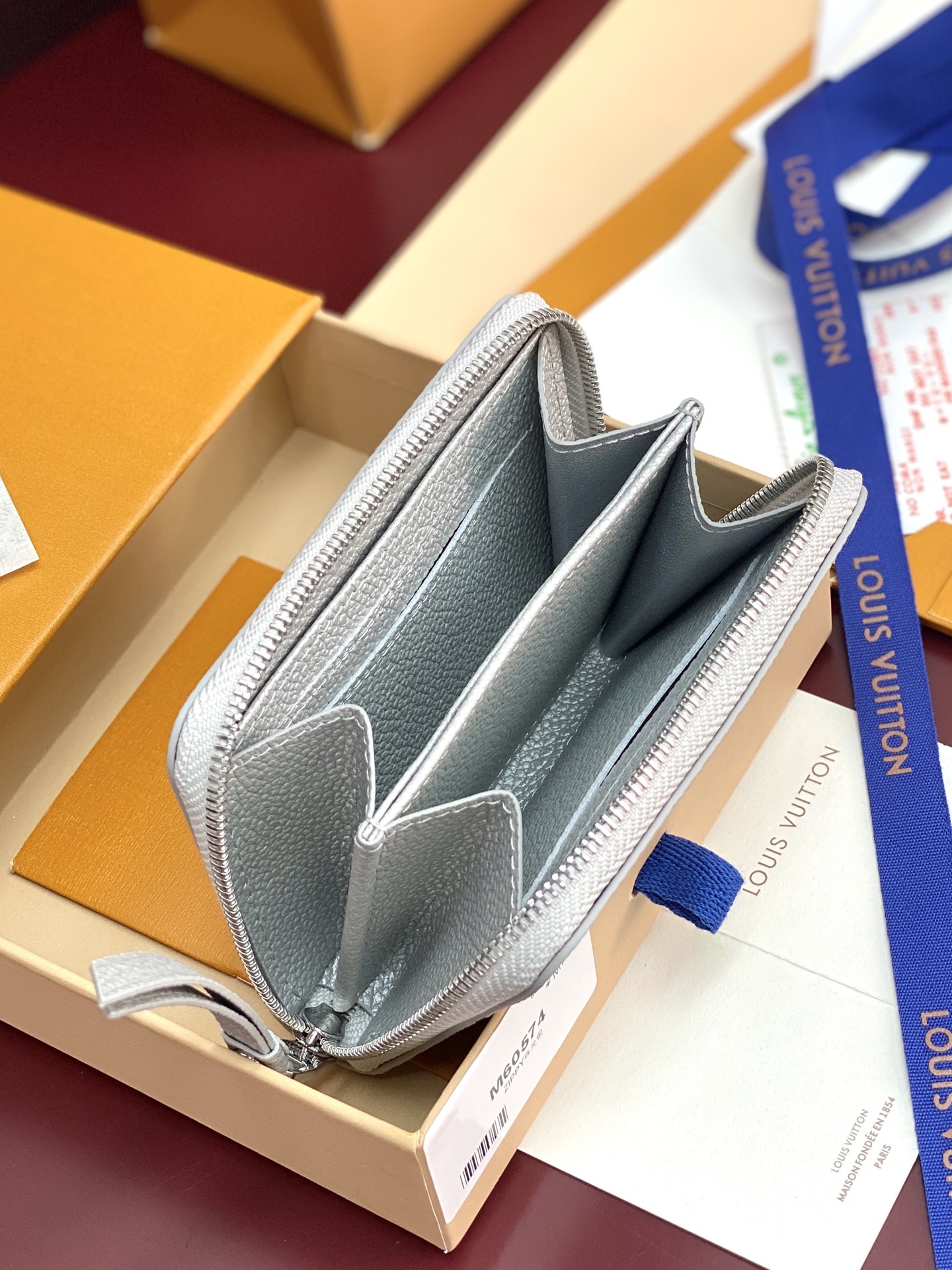 M60574 珠光银！此款拉链零钱包为都市人提供了最理想的选择。包身精巧紧凑，以亮银白色烘托精致质感。可