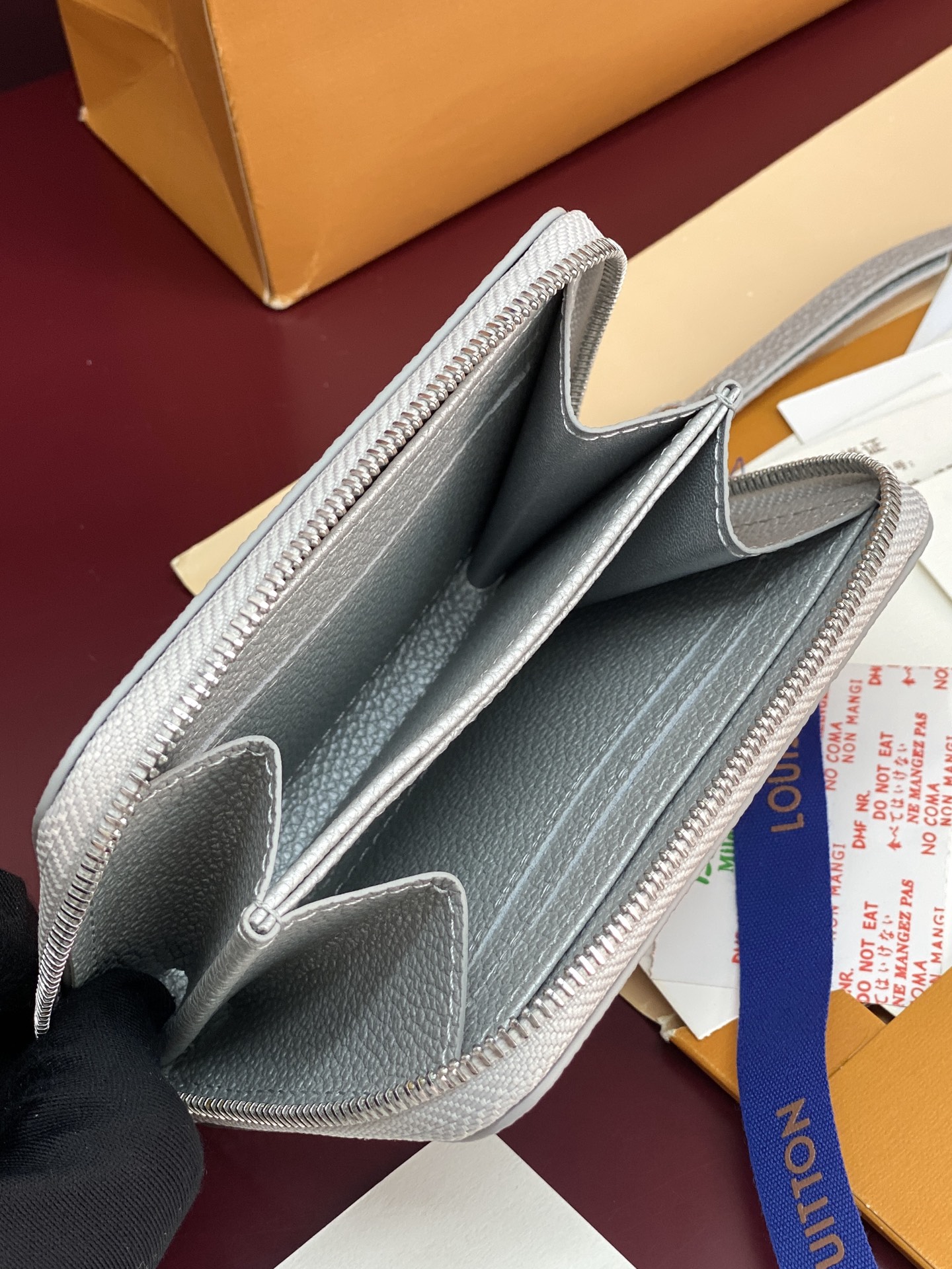 M60574 珠光银！此款拉链零钱包为都市人提供了最理想的选择。包身精巧紧凑，以亮银白色烘托精致质感。可