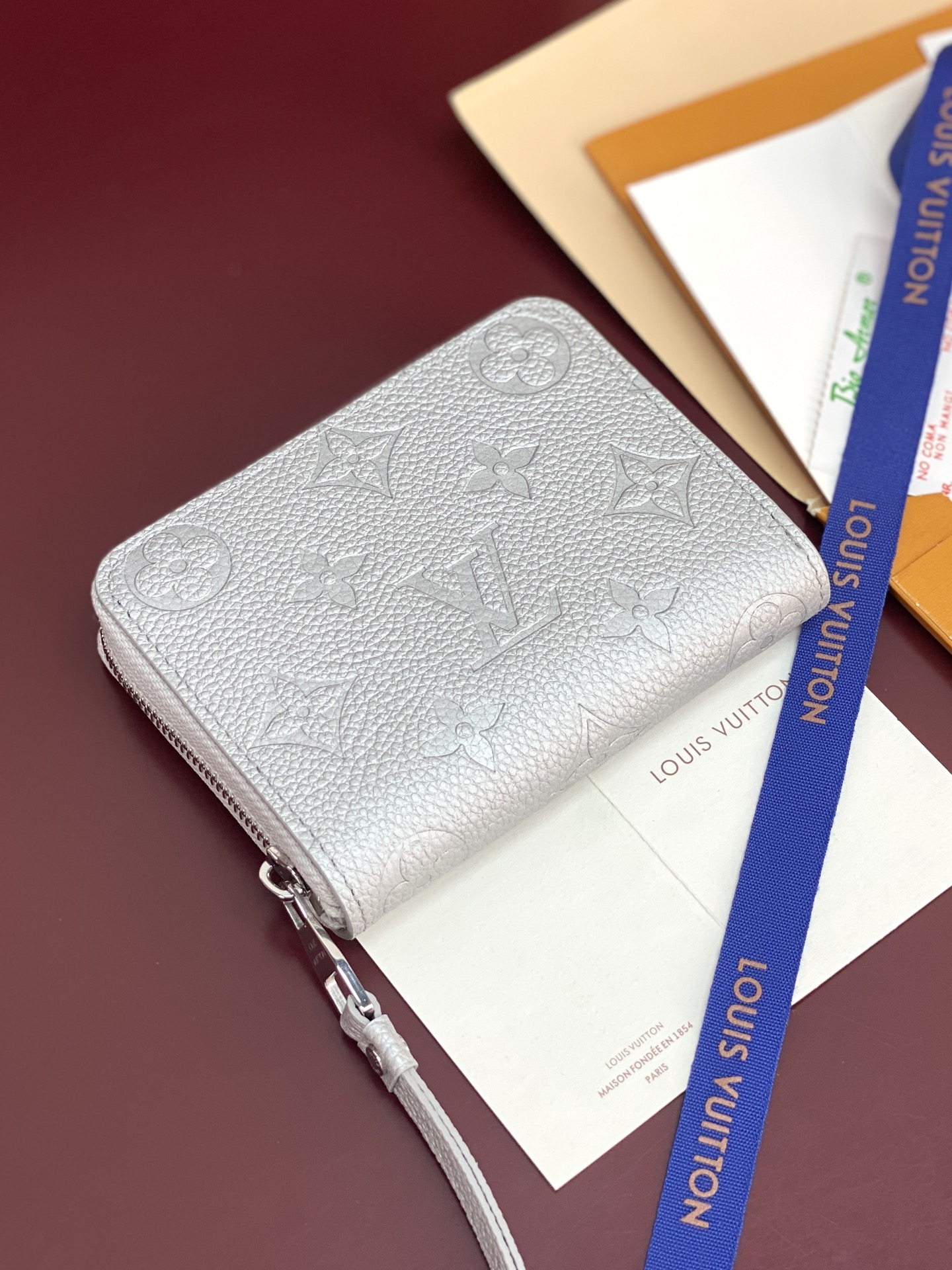 M60574 珠光银！此款拉链零钱包为都市人提供了最理想的选择。包身精巧紧凑，以亮银白色烘托精致质感。可