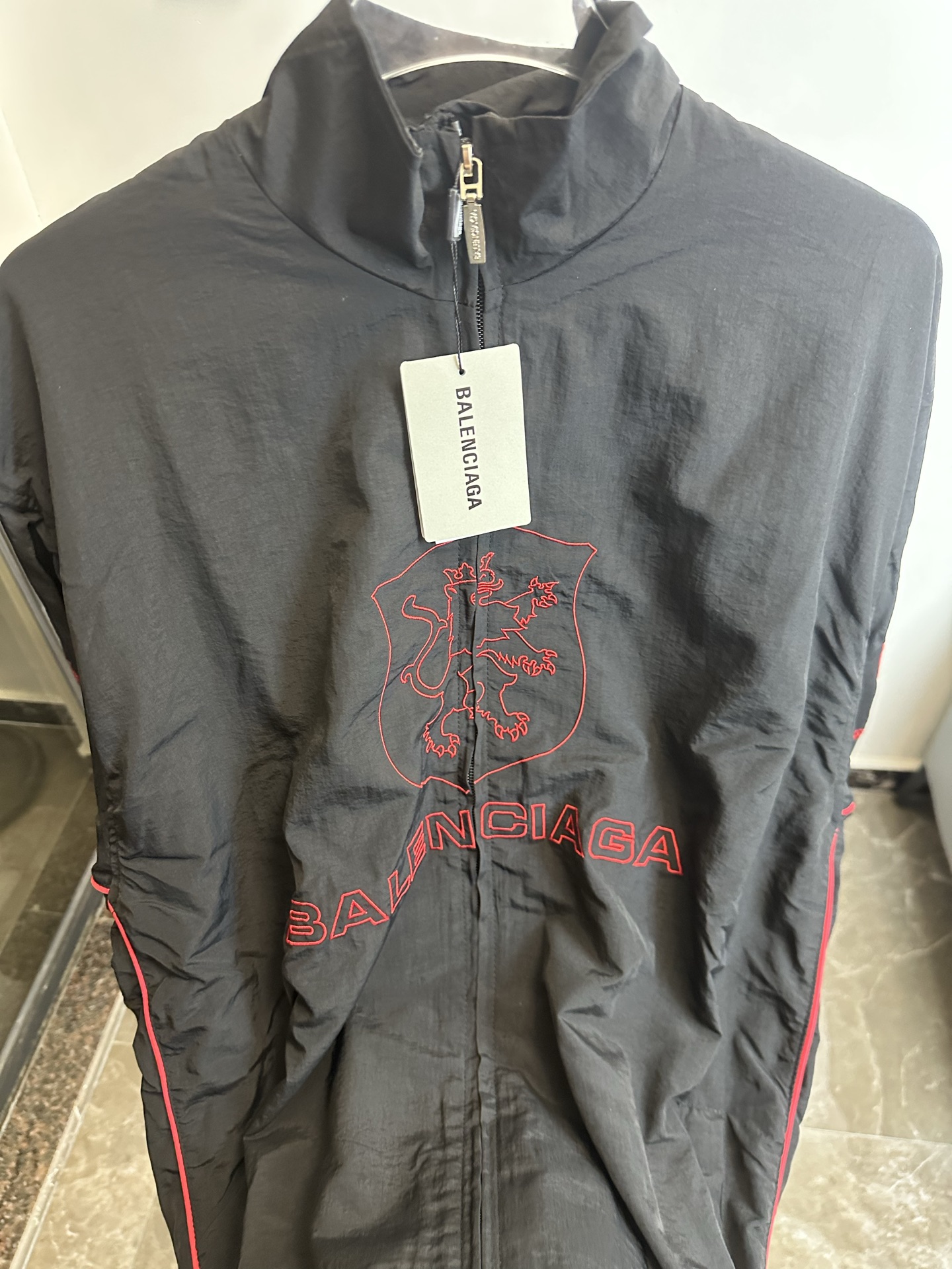 🅿️220【原单】
款号：TT61
【上新】Balenciaga 巴黎世家新款lion club曼联运动冲锋衣外套-

酷盖必备💥| Balenciaga 曼联刺绣冲锋衣
👦潮流玩家们，Balenciaga 这件黑色曼联刺绣冲锋衣真的杀疯了！
⚫经典黑色，百搭王者段位，怎么搭都不出错，轻松拿捏各种风格。冲锋衣版型挺括有型，穿上身气场瞬间两米八，户外感与时尚感并存。
曼联刺绣无疑是最大亮点👏，传承足球精神的同时，为这件冲锋衣赋予了独特的文化底蕴，精致刺绣在黑色基底上格外惹眼，高级感与个性齐飞。
功能性更是杠杠的👍，专业防水面料，下雨天、户外探险都能应对自如；透气设计让你运动出汗后也能保持干爽。拉链顺滑无阻，多口袋方便收纳随身小物件。


🔘颜色：黑色  
🔘Size：S  M  L  XL   现货秒发 详细尺码可查图9