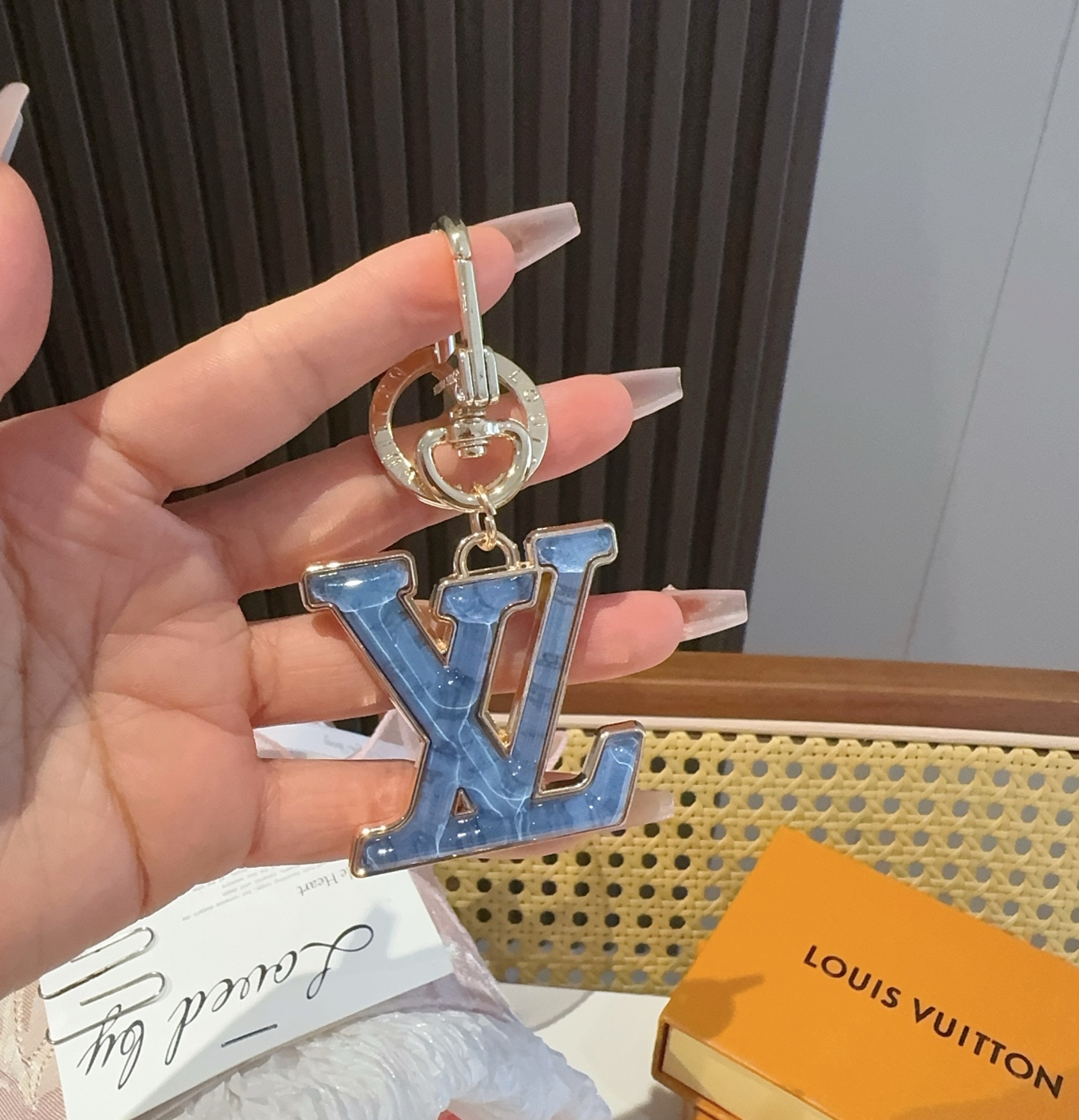  。LV 钥匙扣 包包挂件配饰Gloss 钥匙扣将有机玻璃 LV 字母镶嵌金属之中，其上点缀 Nanog