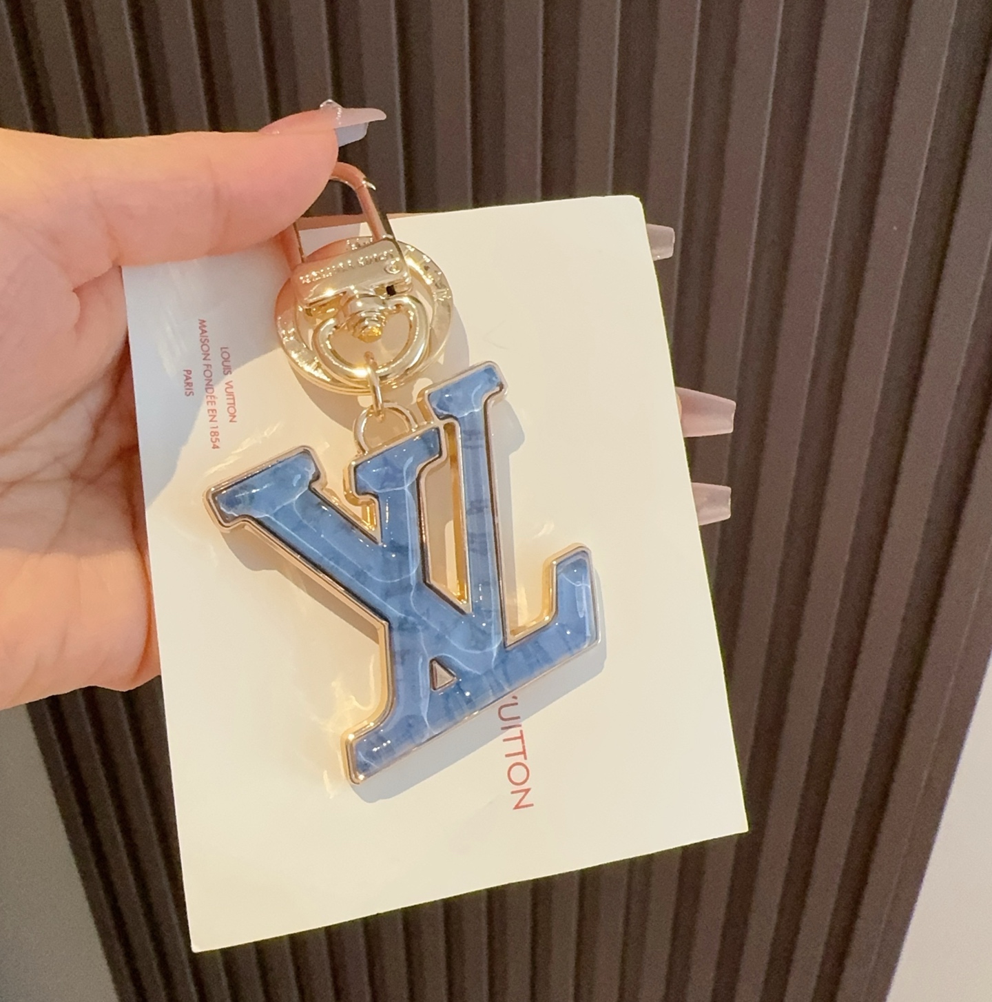  。LV 钥匙扣 包包挂件配饰Gloss 钥匙扣将有机玻璃 LV 字母镶嵌金属之中，其上点缀 Nanog