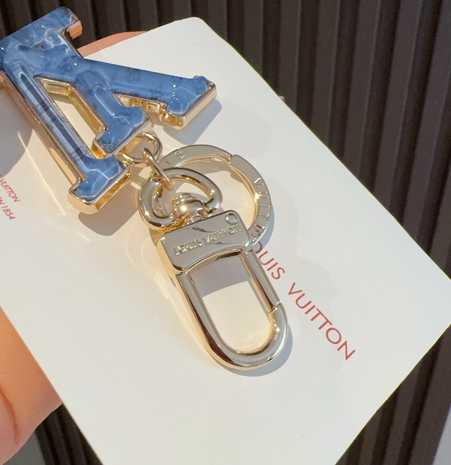  。LV 钥匙扣 包包挂件配饰Gloss 钥匙扣将有机玻璃 LV 字母镶嵌金属之中，其上点缀 Nanog