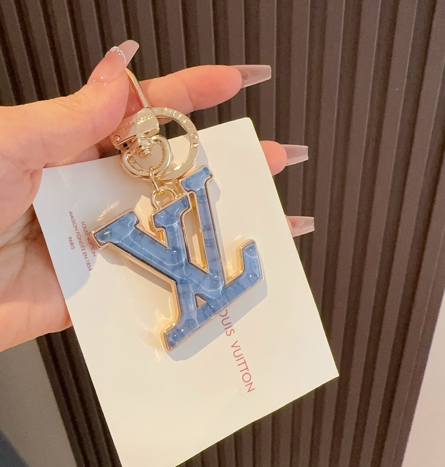  。LV 钥匙扣 包包挂件配饰Gloss 钥匙扣将有机玻璃 LV 字母镶嵌金属之中，其上点缀 Nanog