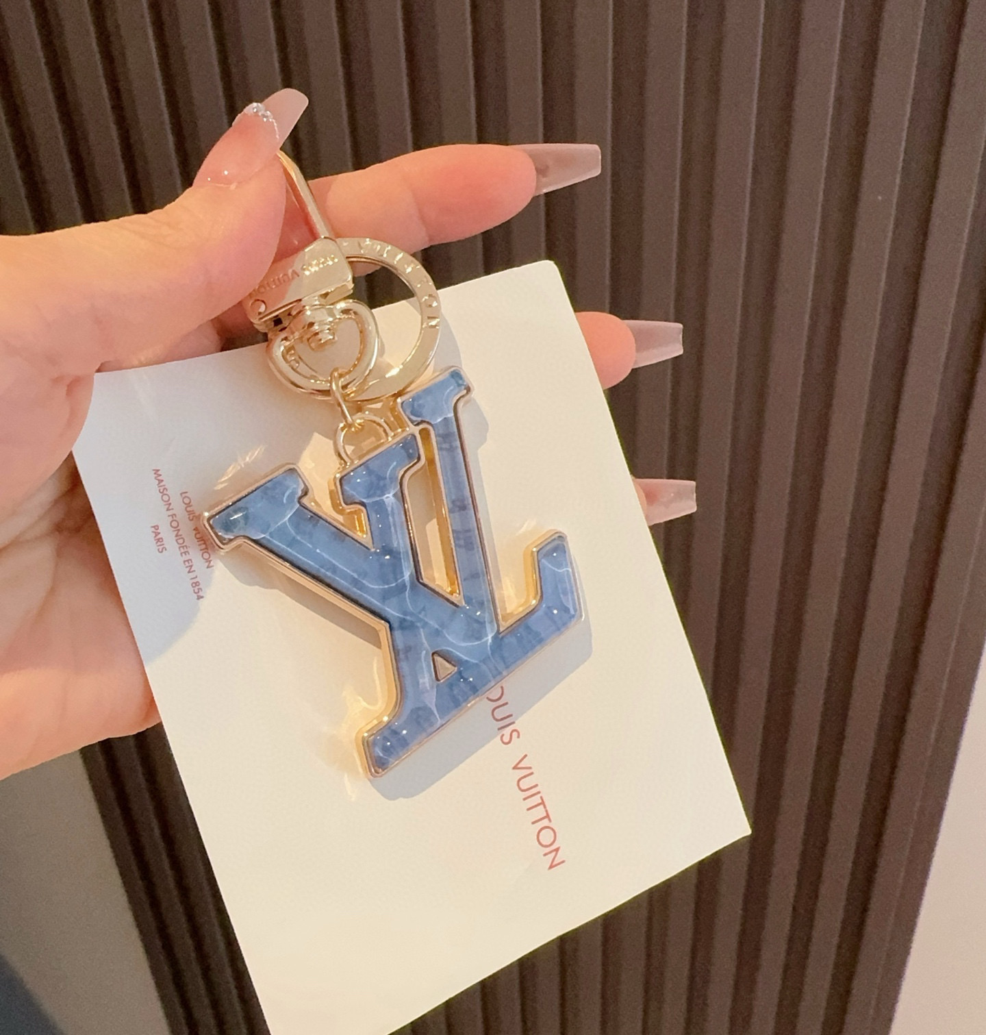  。LV 钥匙扣 包包挂件配饰Gloss 钥匙扣将有机玻璃 LV 字母镶嵌金属之中，其上点缀 Nanog