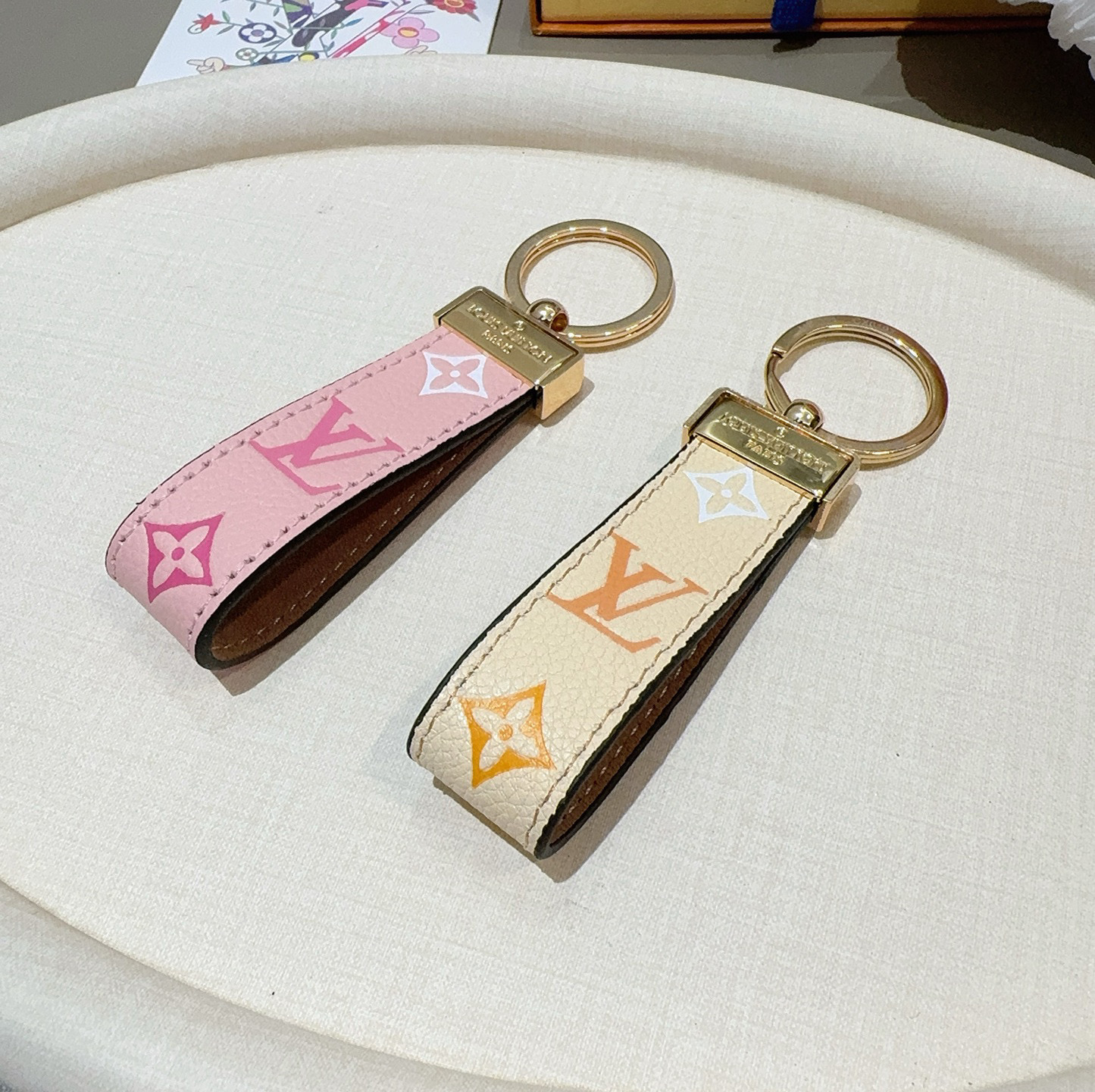 P85 🔥爆款推荐 驴家牛皮压花渐变钥匙扣 LV钥匙扣 车钥匙挂件包包挂饰
 Dauphine Dragonne 钥匙扣彰显金属匠艺与品牌经典标识的融合。标志性 Monogram 帆布烘托 Dauphine 搭扣，与皮具系列同名手袋相得益彰。