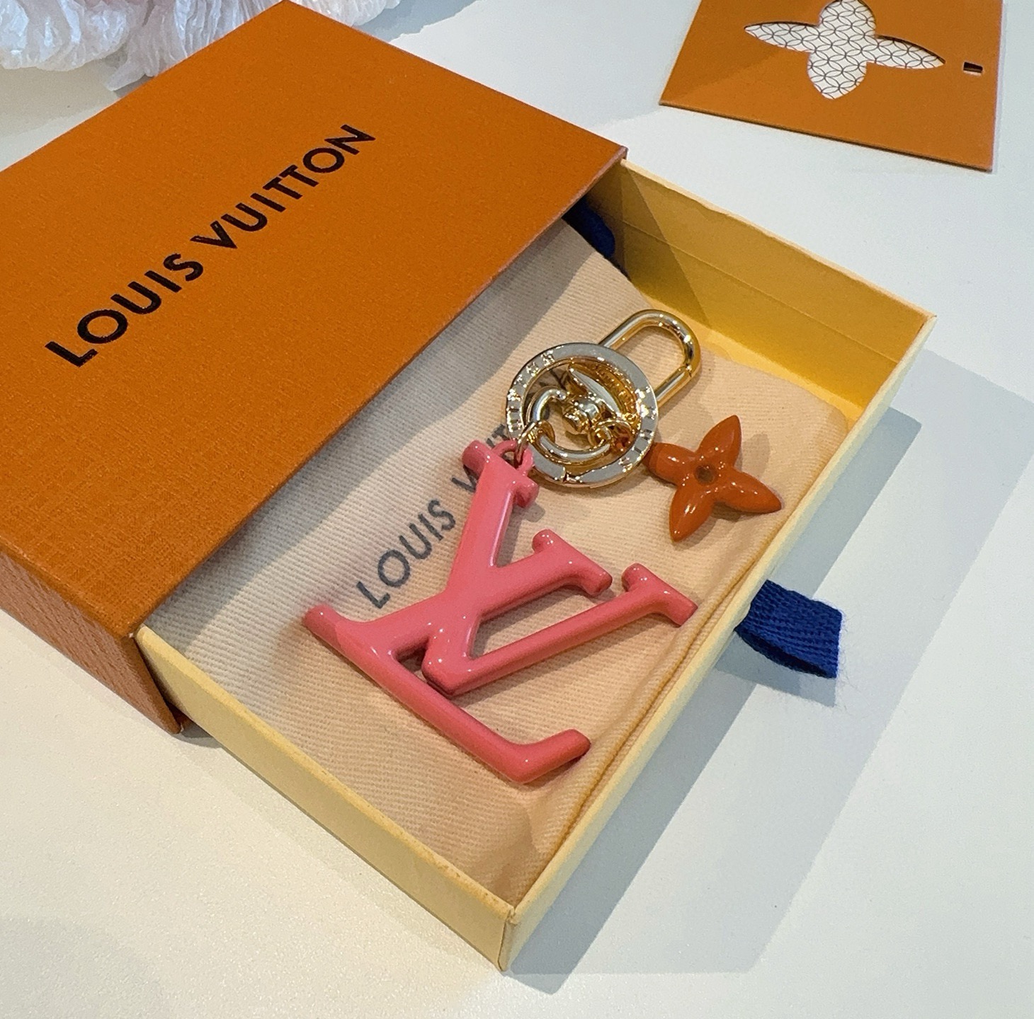 LV字母挂件 PoPFlower包和钥匙扣的魅力非常适合为皮革配饰增添标志性的色彩，其特点是金色金属钩环