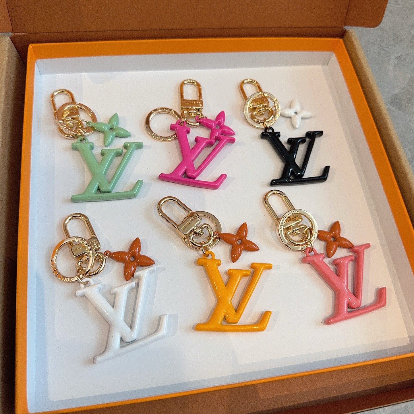 LV字母挂件 PoPFlower包和钥匙扣的魅力非常适合为皮革配饰增添标志性的色彩，其特点是金色金属钩环