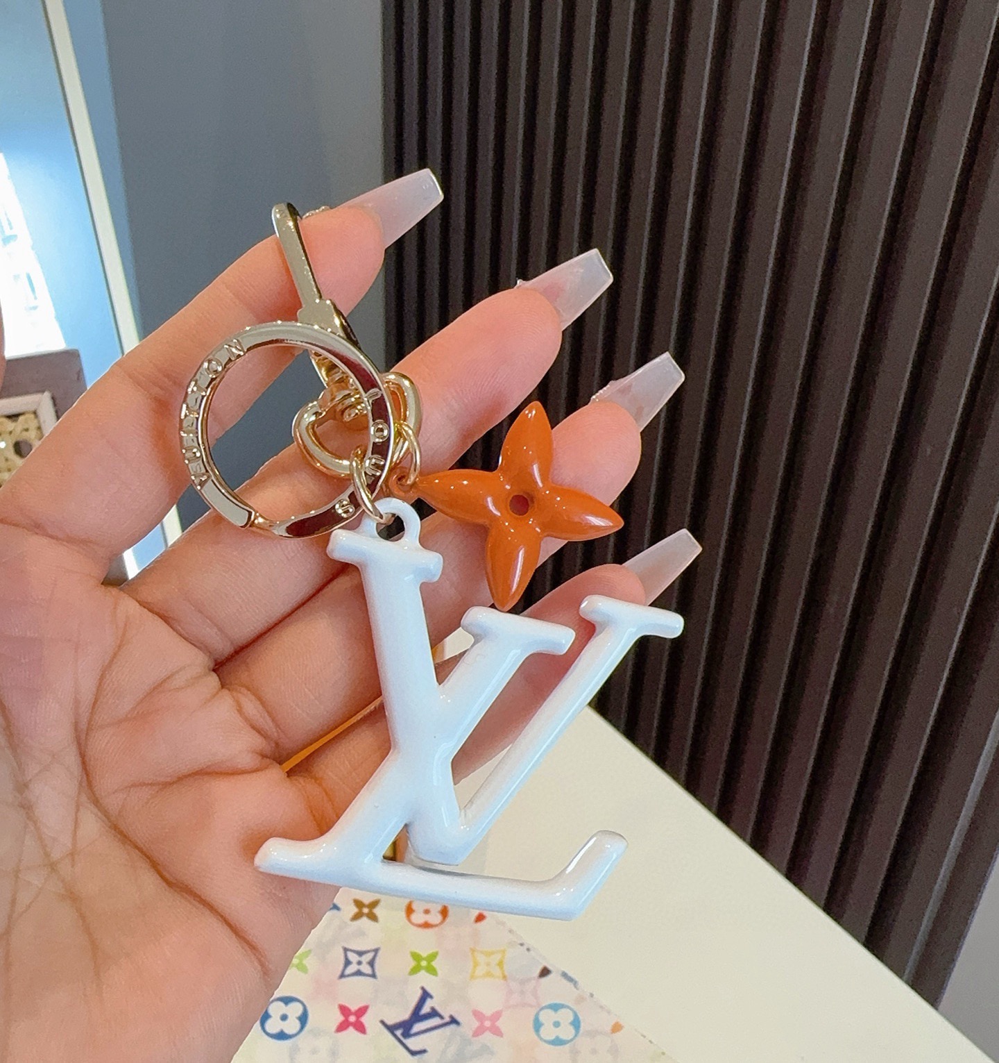 LV字母挂件 PoPFlower包和钥匙扣的魅力非常适合为皮革配饰增添标志性的色彩，其特点是金色金属钩环