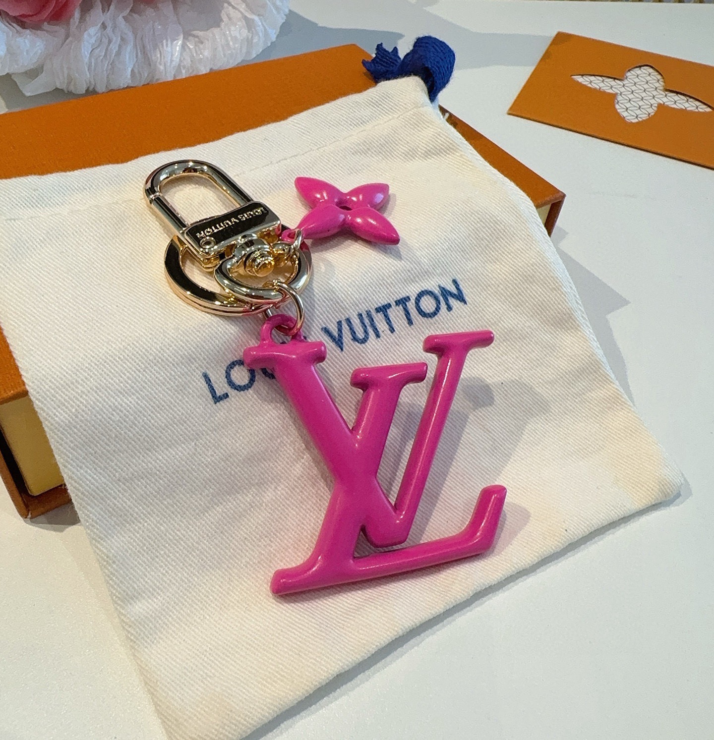 LV字母挂件 PoPFlower包和钥匙扣的魅力非常适合为皮革配饰增添标志性的色彩，其特点是金色金属钩环