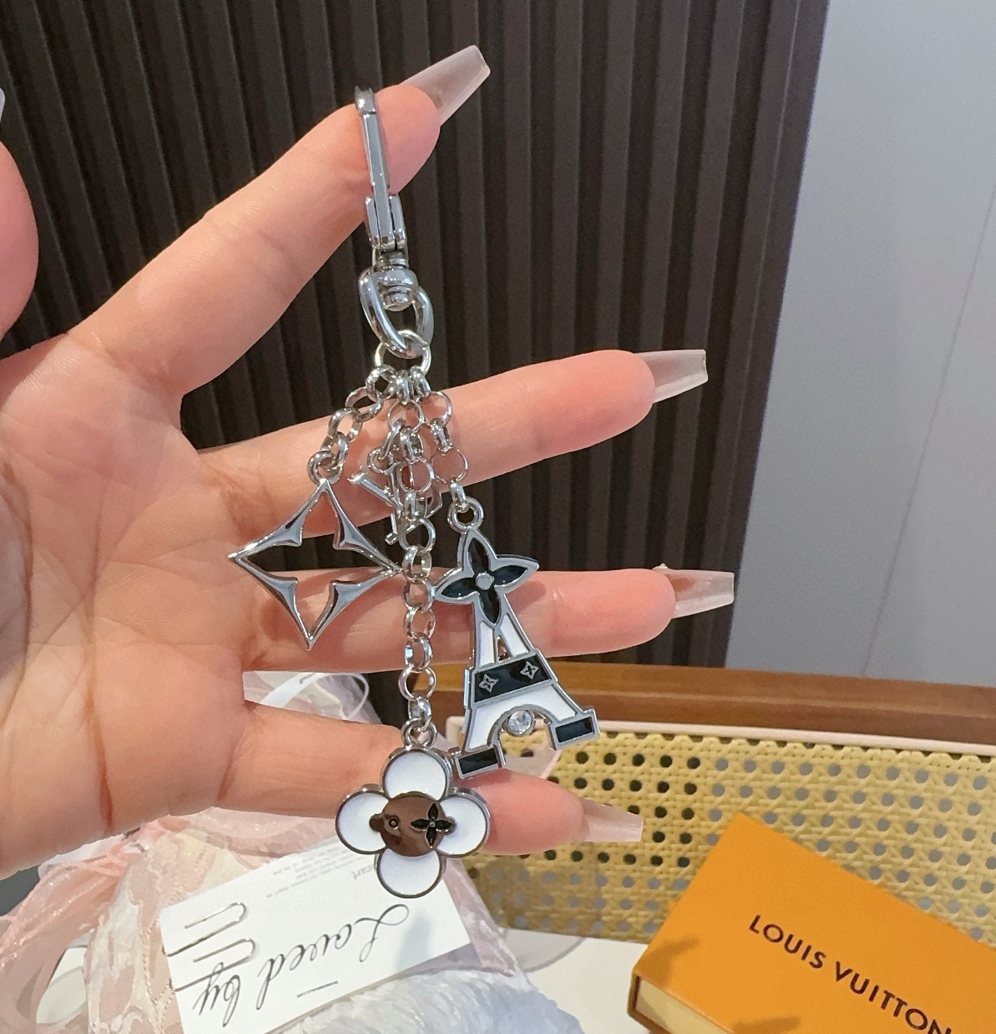 Lv包饰与钥匙扣 包包挂件LV 巴黎铁塔精巧链条四叶草铭牌装饰，与小号尖瓣 Monogram 花卉相映成